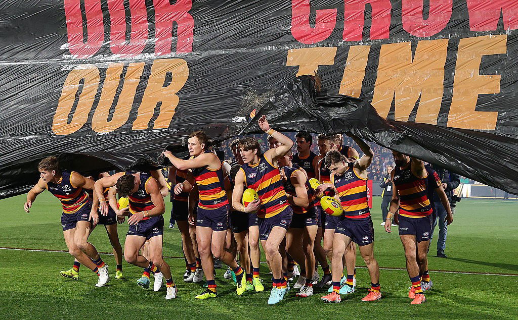 Adelaide players run through the banner