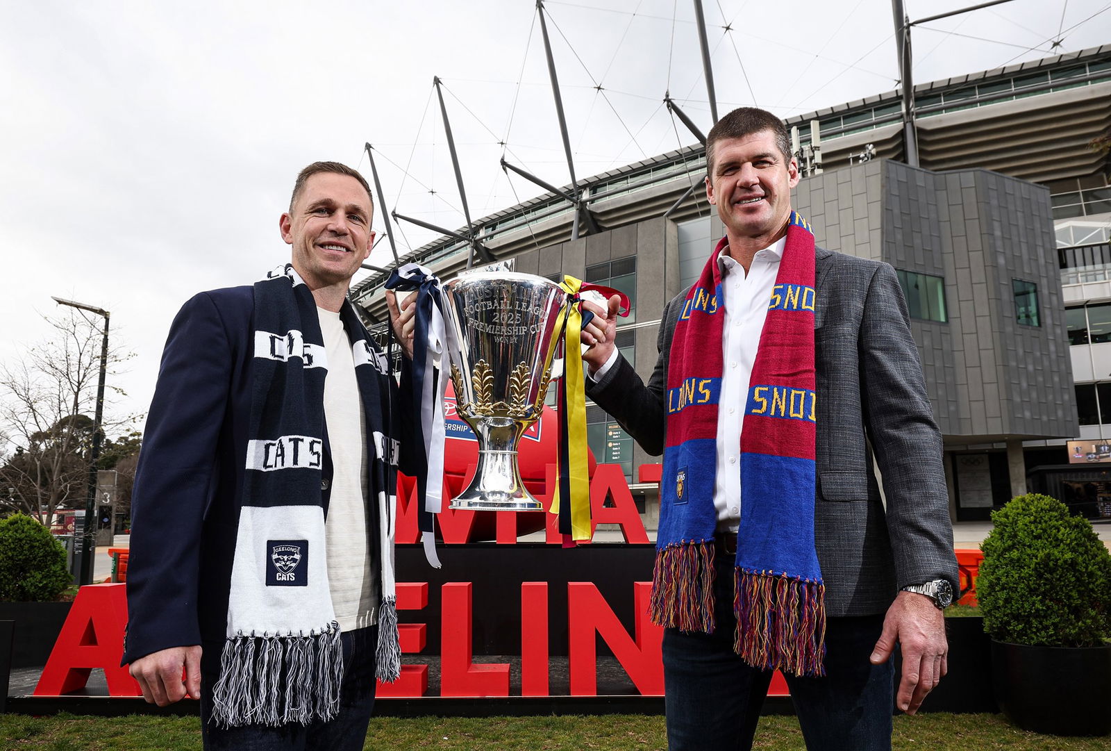 Former premiership players Joel Selwood and Jonathan Brown hold this year's premiership cup outside the MCG.
