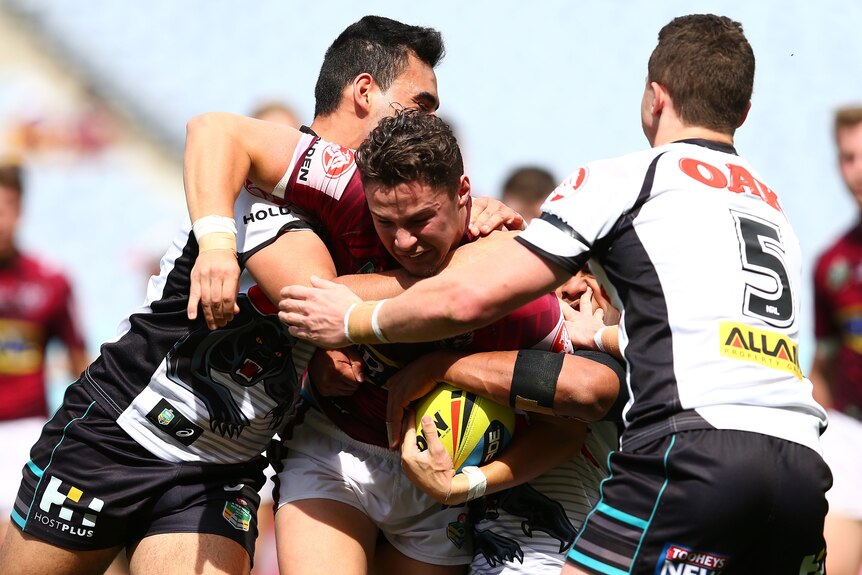 A man takes on the defenders during a rugby league match