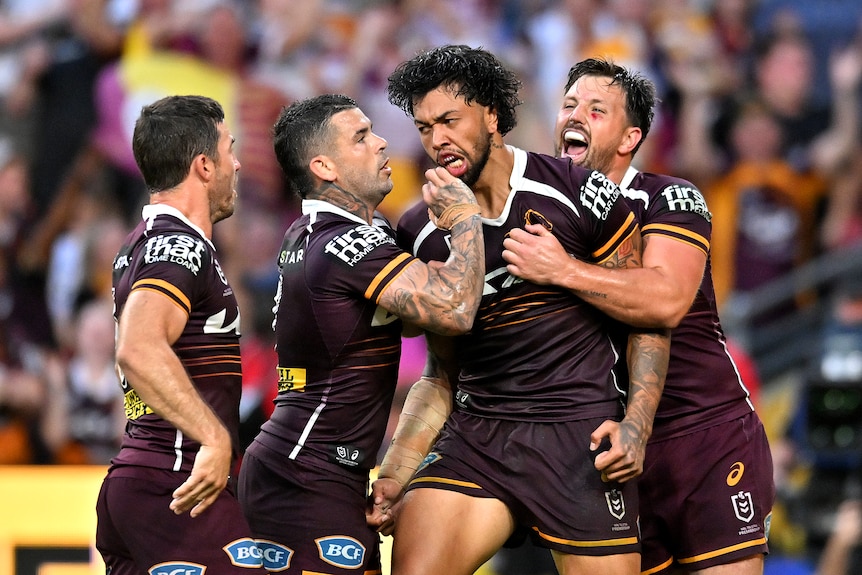 Brisbane Broncos players embrace Xavier Willison after a try in an NRL game.