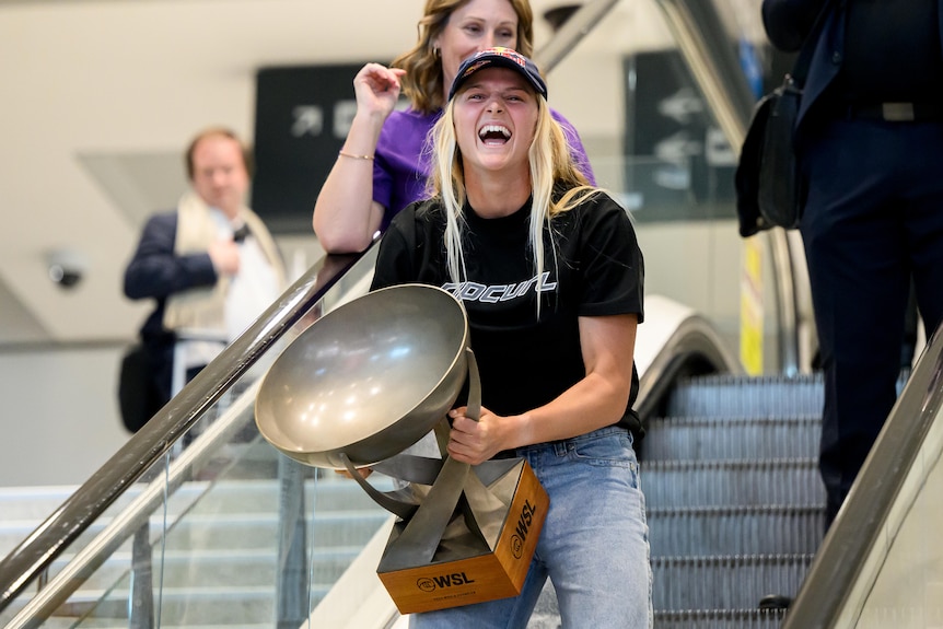 Women's world surfing champion Molly Picklum holds her world champion trophy at Sydney Airport