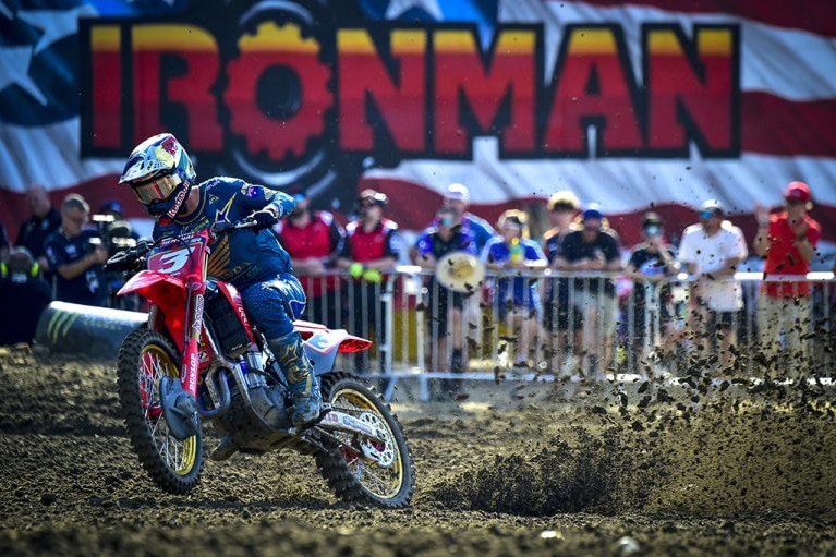 A motocross rider riding his bike fast and flicking up dirt behind him on a motocross track.