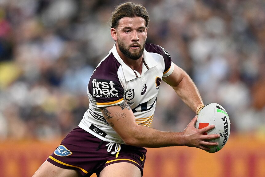 Patrick Carrigan holds the ball in two hands during a Broncos' NRL match.