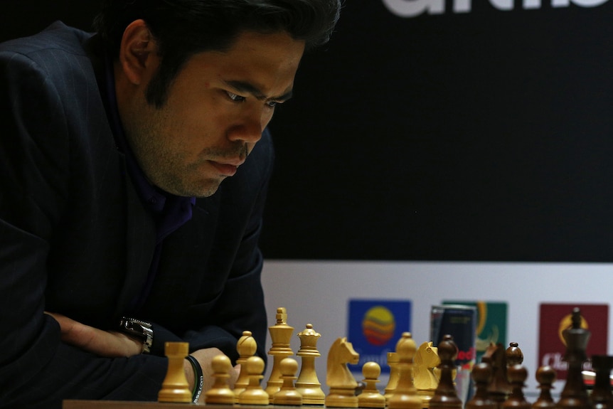 Chess player hovers over the board. 