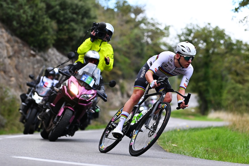 Tadej Pogačar rides his bike with a TV camera behind him.