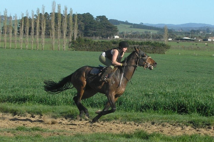 Katherine when she was a young woman riding a race horse in a jockey stance.