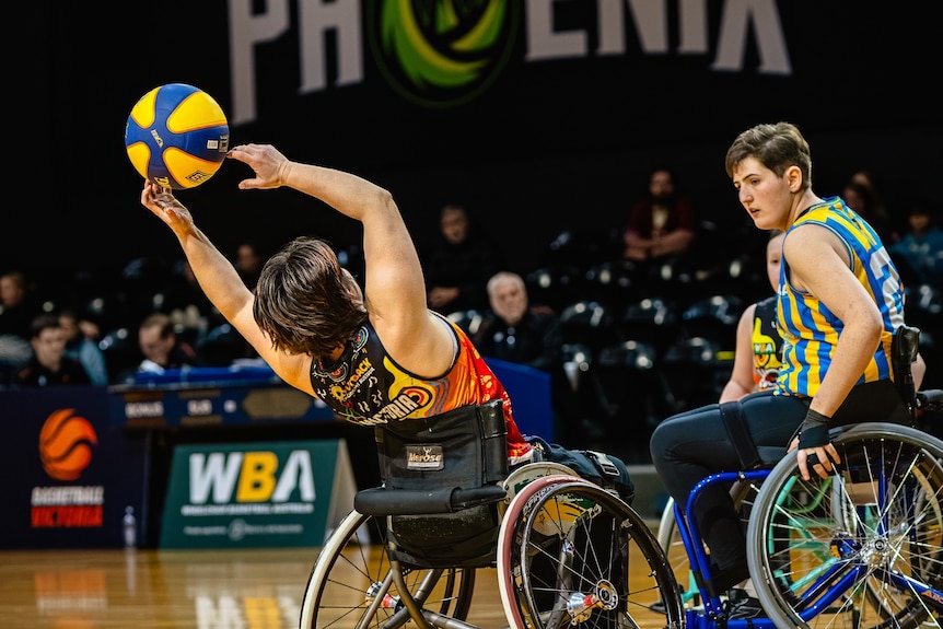 Katherine Reed leans back in her wheelchair to catch a basketball on the basketball court.