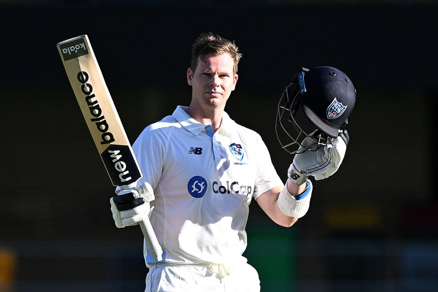 Steve Smith has his bat and helmet raised after a century