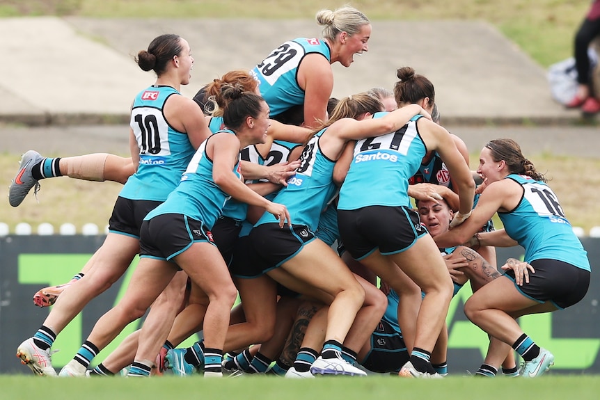 Port Adelaide AFLW players surround Geema Houghton as they celebrate her 100th goal.
