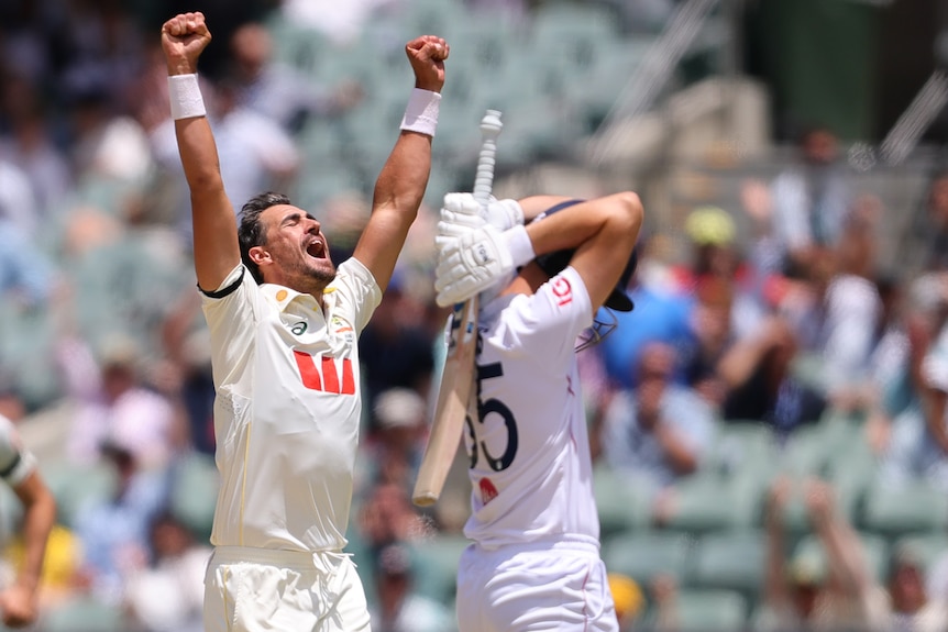 A cricket celebrates a wicket with his arms outstretched, batter looks distraught.