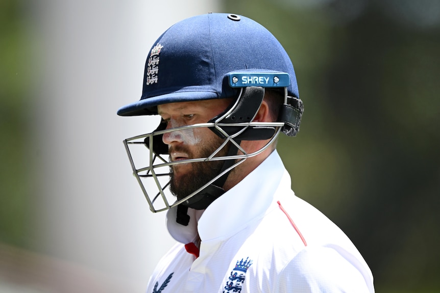 Ben Duckett looks dejected. wears helmet and cricket whites. 