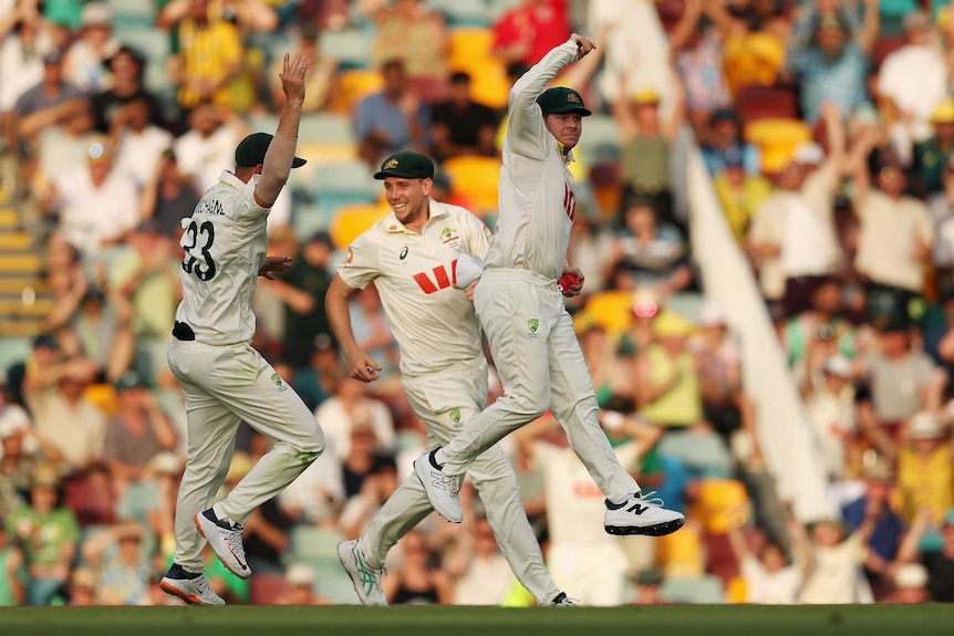 Australia fielder Steve Smith jumps to celebrate a wicket with Test teammates.