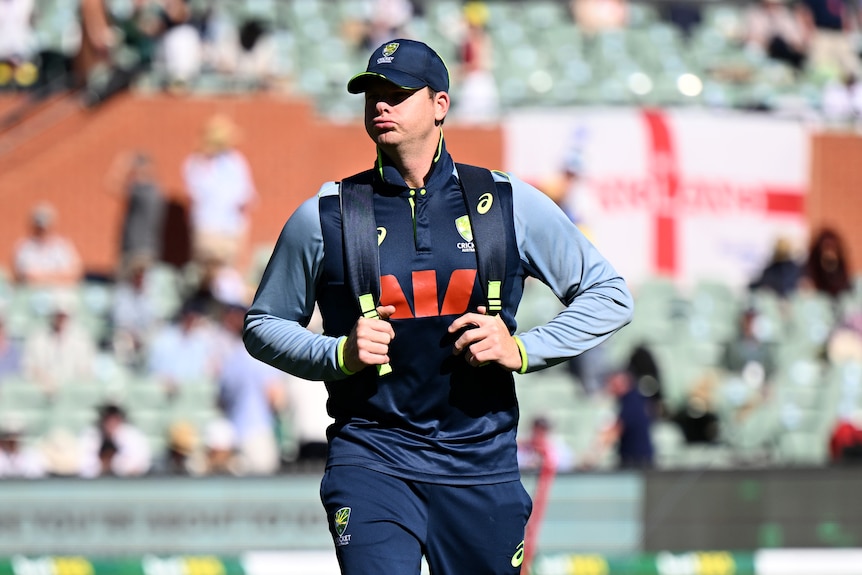 A cricket player in training gear walks off the field.