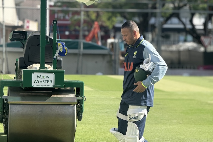 Usman Khawaja walks across a green after a nets session