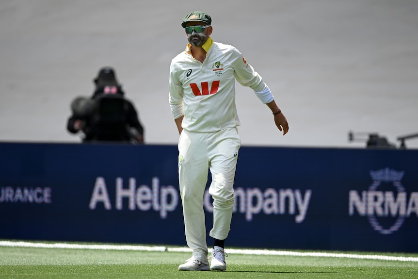 Australia fielder Nathan Lyon holds his hamstring in the field.
