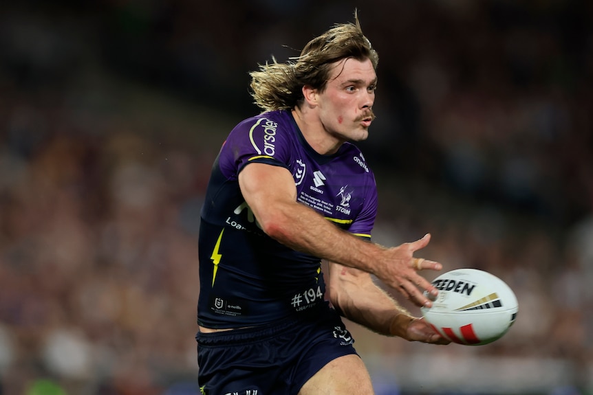 NRL player running with the ball, passing to his left.