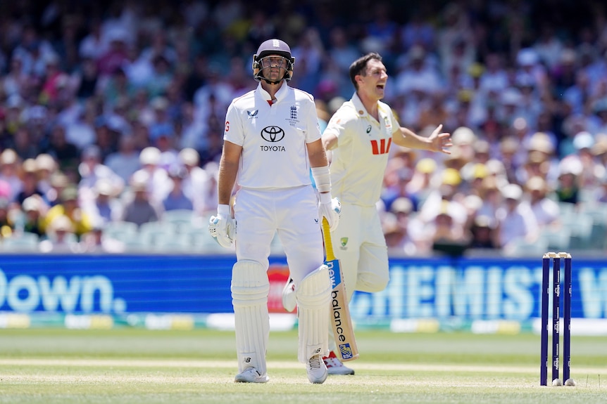 England batter Joe Root throws his head back as Pat Cummins celebrates during a cricket Test.