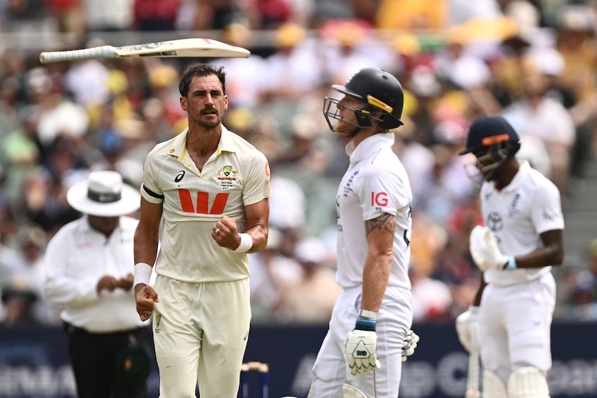 Mitchell Starc celebrates the wicket of Ben Stokes as he throws his bat in the air.