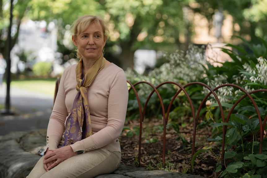 A lady sitting and smiling off camera.