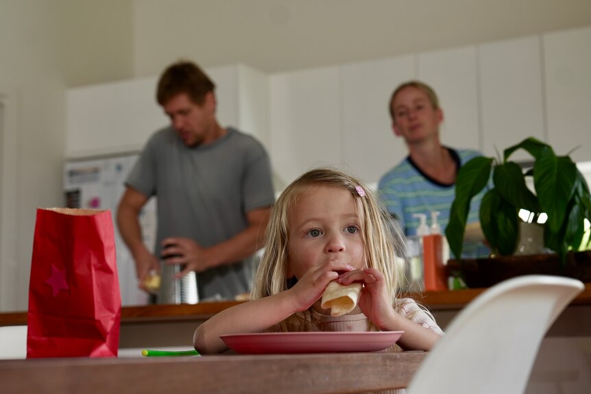 A young girl eating an English muffin