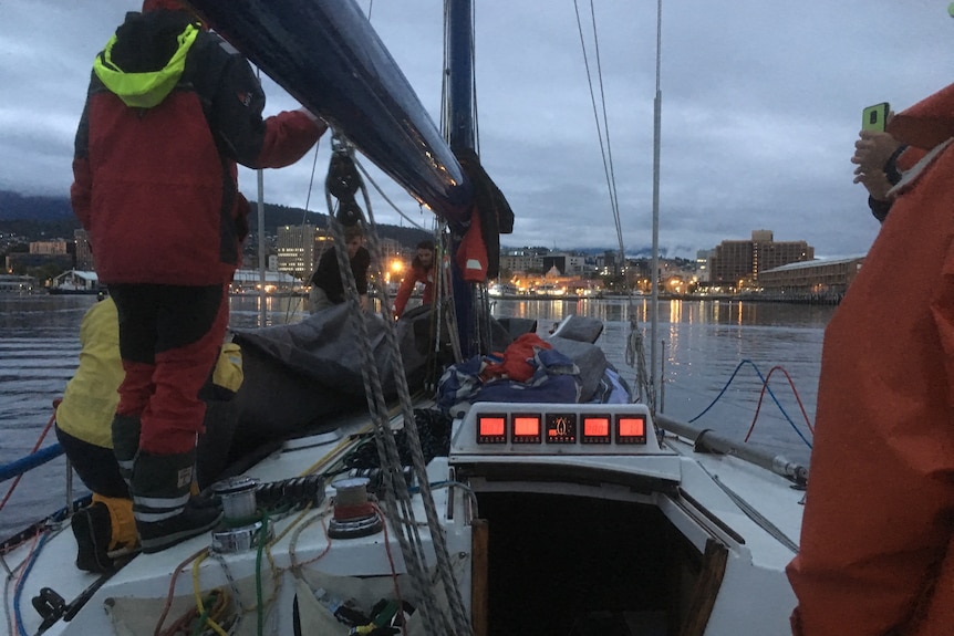 A view from on board a boat, with the crew on deck preparing the boat as it comes to shore at the end of a big race.
