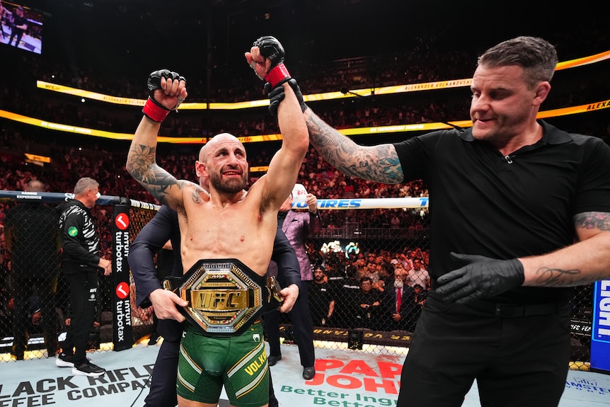 A man raises his arms in triumph after winning an MMA fight 