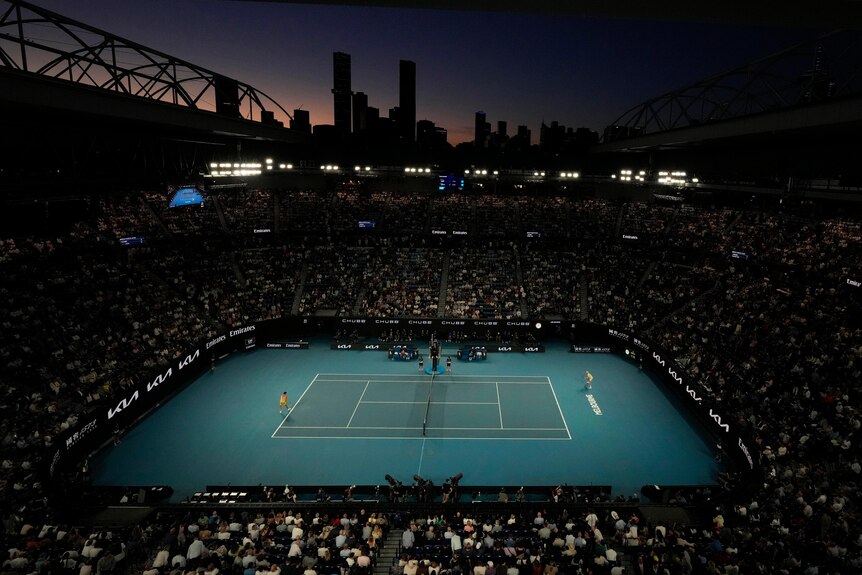 A big shot view of Rod Laver Arena at night during the Aus Open with Melbourne skyline in the background