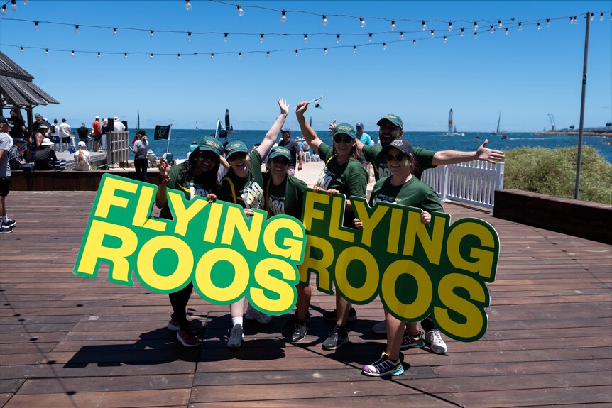 People posing for a picture holding banners saying 'Flying Roos'