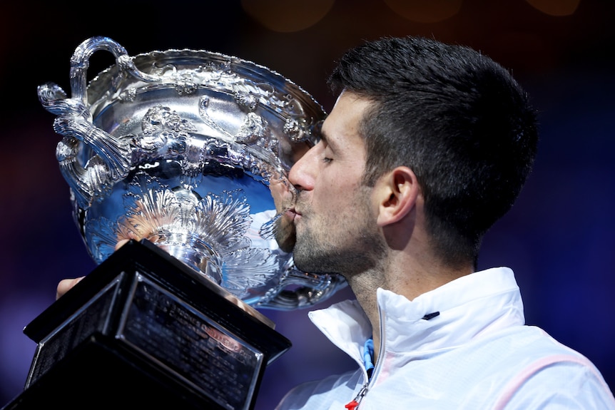Novak Djokovic kisses the Australian Open trophy.