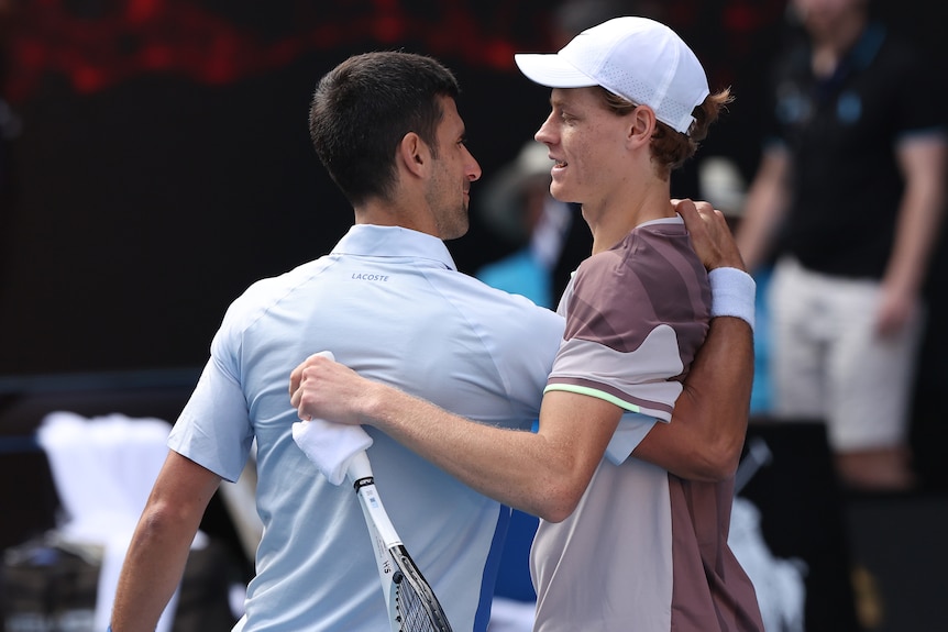 Jannik Sinner and Novak Djokovic embrace at the net at the 2024 Australian Open.