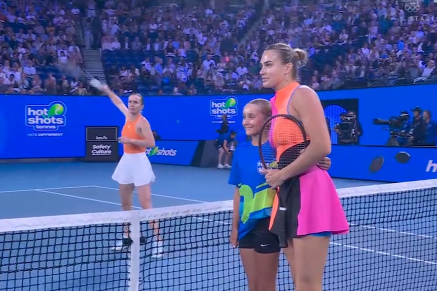 Aryna Sabalenka poses for a photo with a ballkid while Elina Svitolina warms up before their Australian Open semifinal.