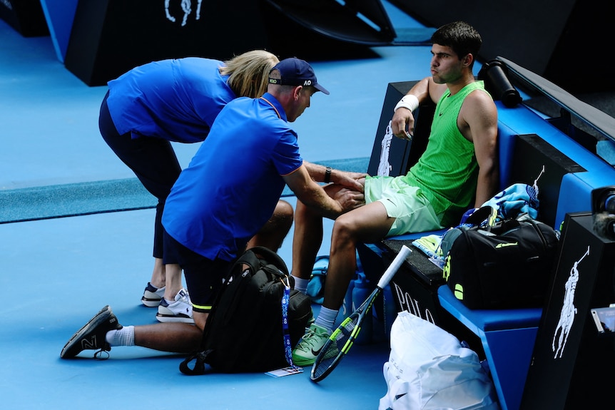Carlos Alcaraz getting his leg massaged by a physio on court