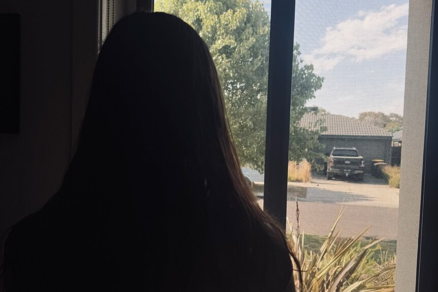 A woman stares out a window in sillouete