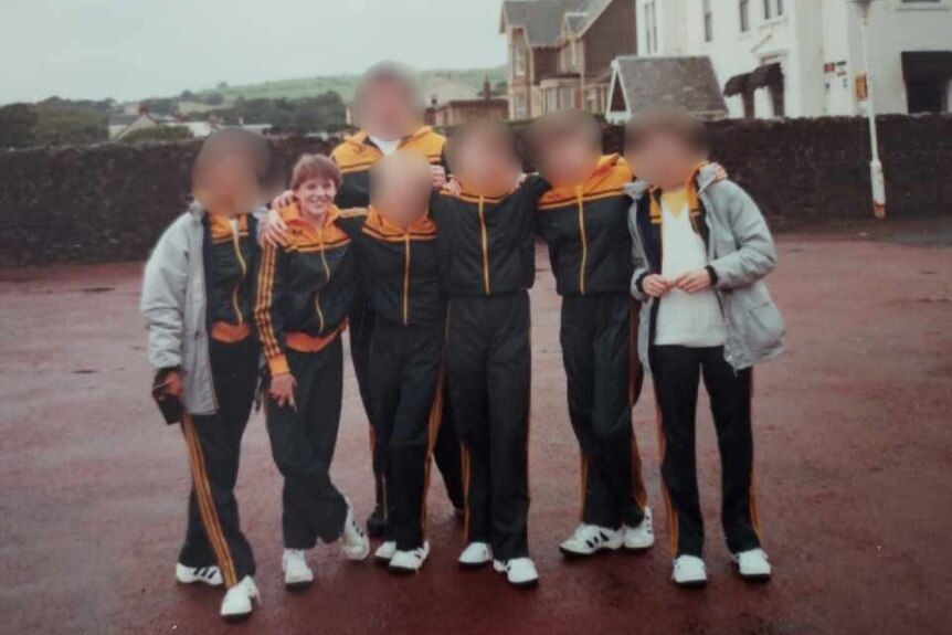 A group of girls pose for a photograph whilst wearing AIS tracksuits.