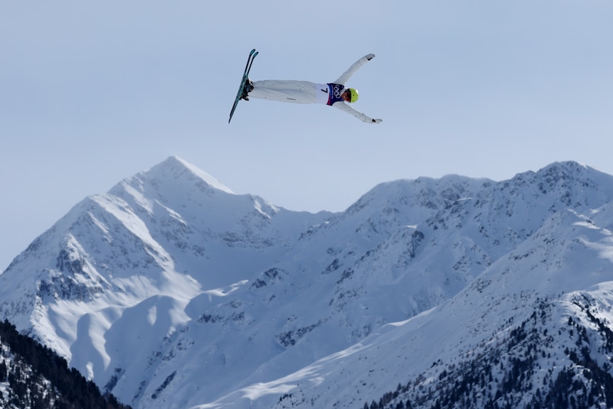A female skiier soars the air in an alpine setting.