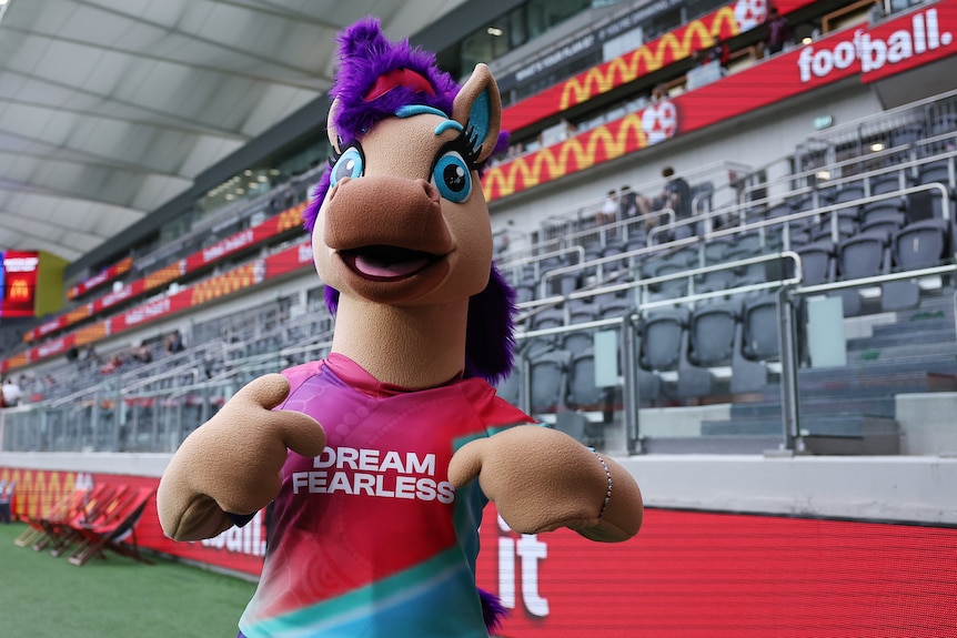 A mascot horse with a purple mohawk and a tshirt that says 'dream fearless'