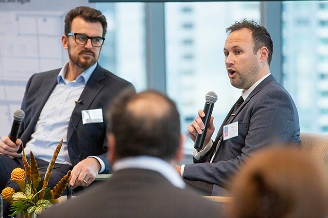 Adam Karg speaks into a microphone at a talking event.