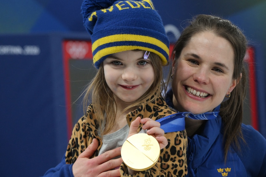Gold medallist Anna Hasselborg of Sweden celebrates with her daughter after the Women's Curling Victory Ceremony
