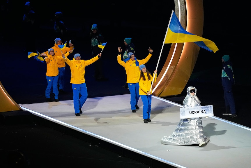 Anastasia Kucherova carries the sign as she leads out athletes from the Ukraine at opening ceremony.