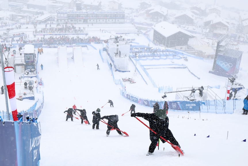 Workers clear the snow from the moguls course
