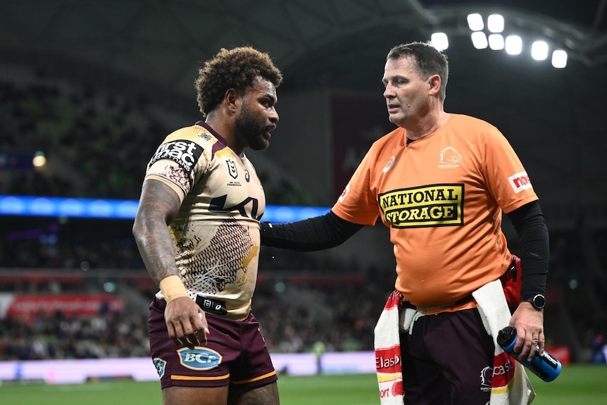 Ezra Mam of the Broncos leaves the field with an injury, helped by a trainer