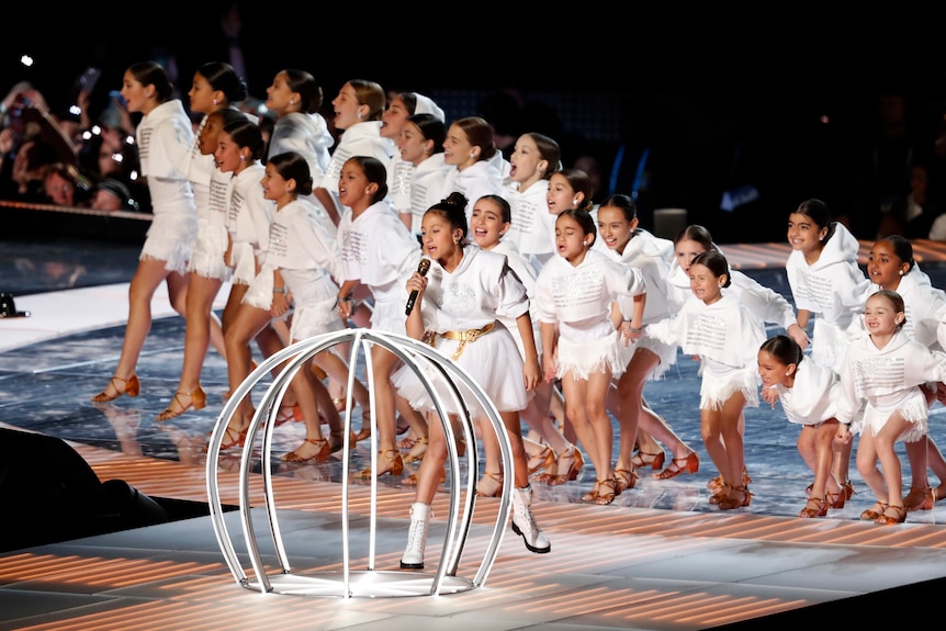 Children performing on stage, with a prop cage