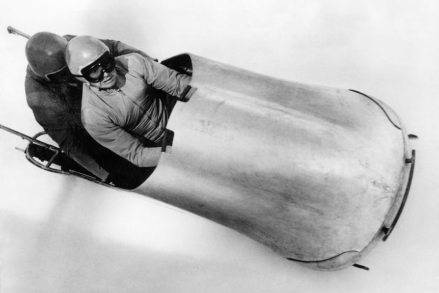 Eugenio Monti and Renzo Alverà in a bobsled. Black and white image.