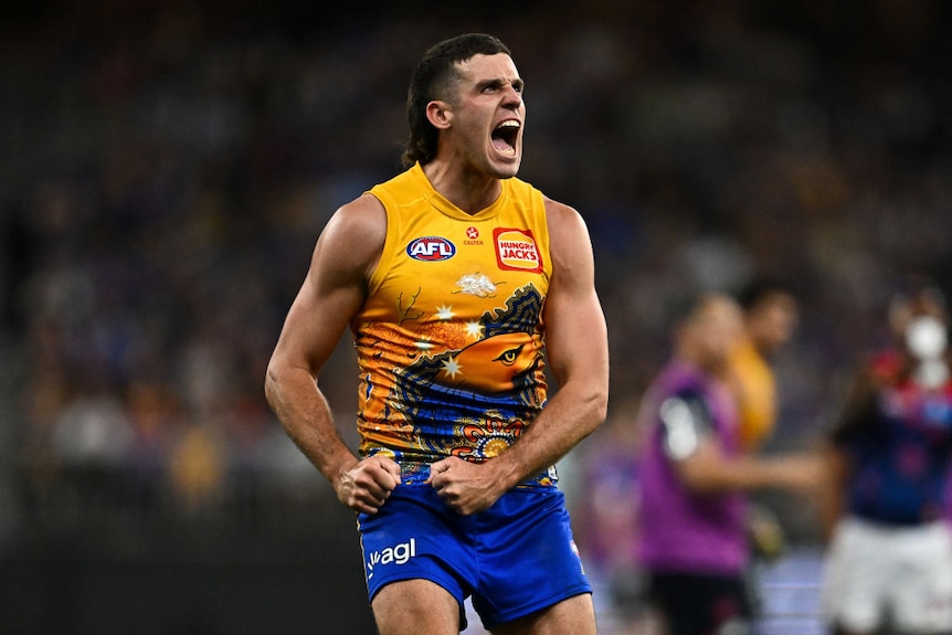 Jake Waterman yells, fists clenched while on the field wearing footy jumper and shorts.