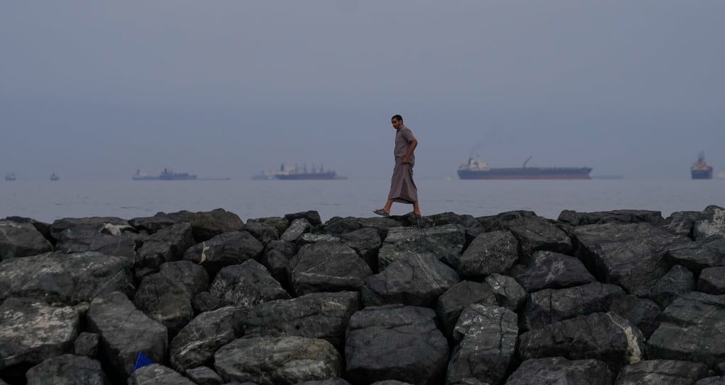 A man walks along the shore in Khor Fakkan, United Arab Emirates, as oil tankers and cargo ships line up in the Strait of Hormuz on Wednesday. Photo: AP A man walks along the shore in Khor Fakkan, United Arab Emirates, as oil tankers and cargo ships line up in the Strait of Hormuz on Wednesday. Photo: AP
