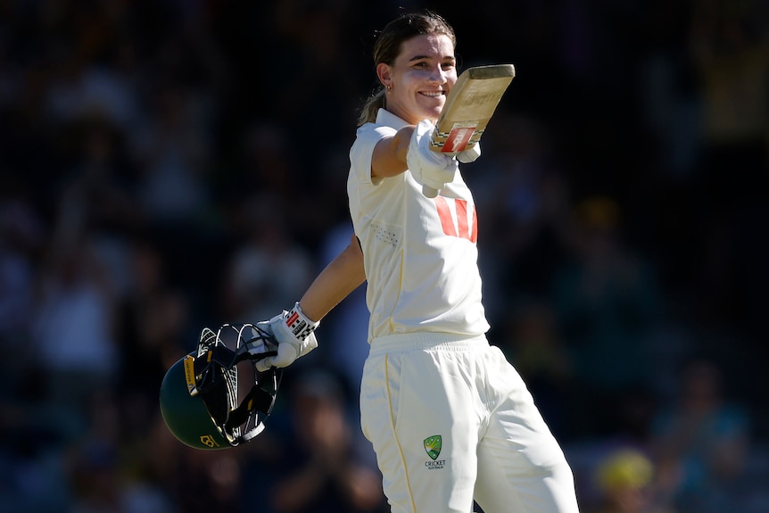 Annabel Sutherland smiles and waves the bat towards the crowd.