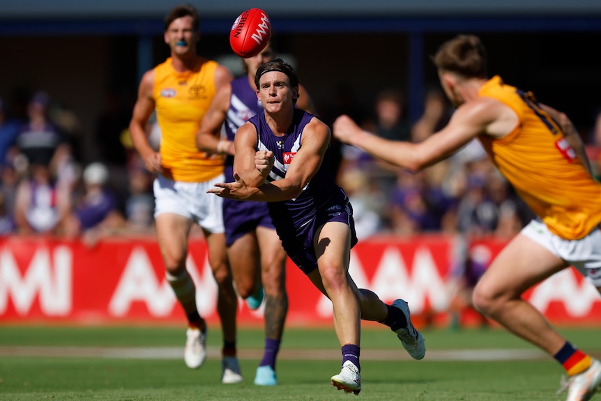 Caleb Serong handballs the football during a pre-seaosn match between the Fremantle Dockers and Adelaide Crows.