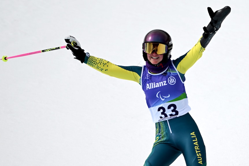 An Australian para-alpine skier smiles and waves her ski after completing a giant slalom run at the Winter Paralympics.