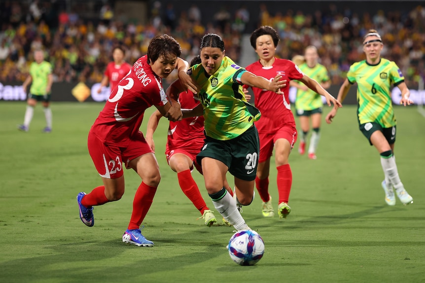 Matildas captain Sam Kerr is held back by a North Korean defender as they chase the ball