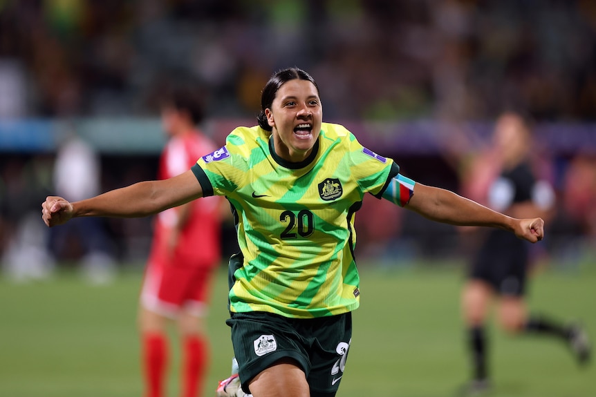 Matildas captain Sam Kerr runs with arms outstreched as she celebrates scoring